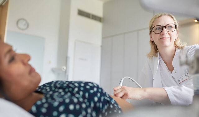 Eine Ärztin führt eine Ultraschalluntersuchung bei einer Schwangeren durch. 