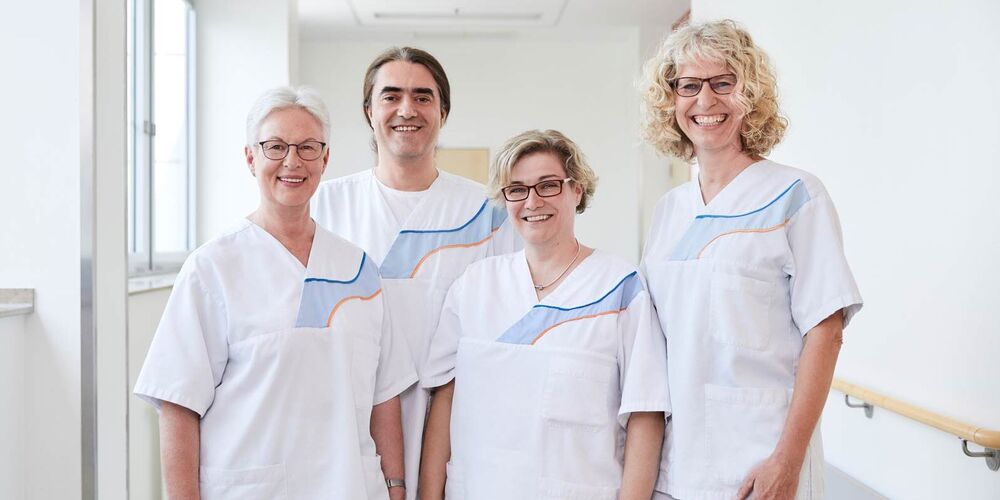 Team der Onkologie, welches aus drei Frauen und einem Mann besteht. Alle vier gucken lächelnd in die Kamera. 
