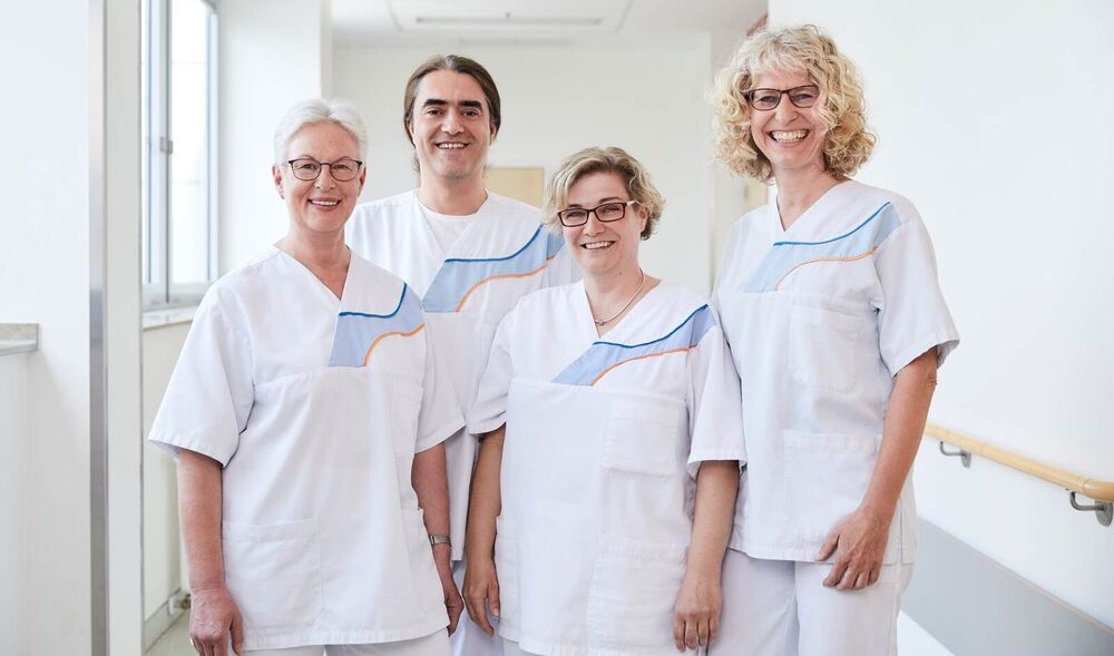 Team der Onkologie, welches aus drei Frauen und einem Mann besteht. Alle vier gucken lächelnd in die Kamera. 
