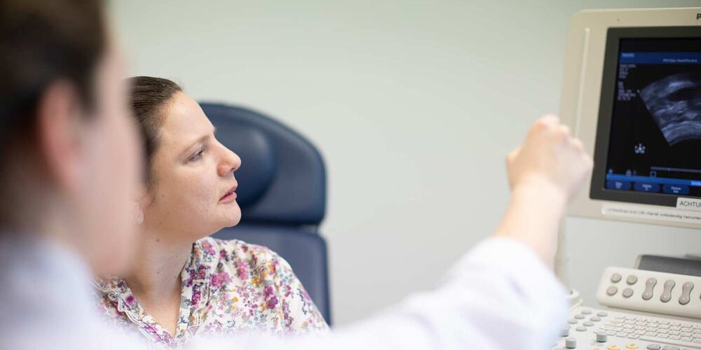 Zwei Frauen schauen auf einen Computer auf dem ein Ultraschall zu sehen. Die Ärztin zeigt der Patientin etwas auf diesem.