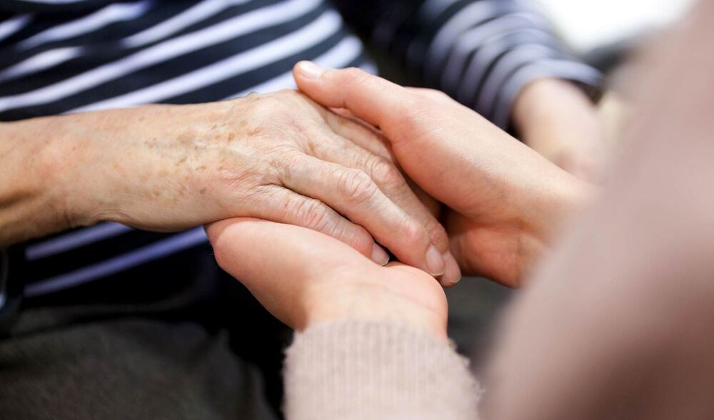 Zwei Hände, die eine andere Hand behutsam halten. 