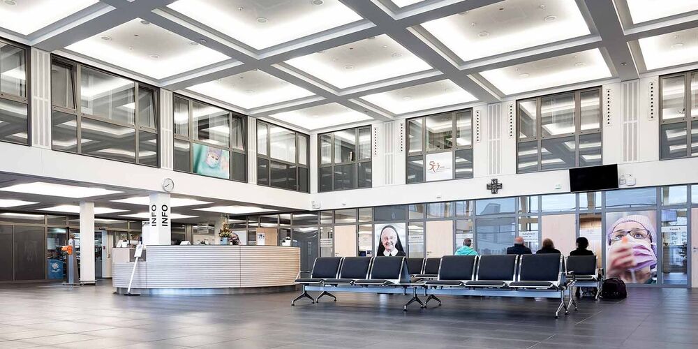 Eingangsbereich des Johanna-Etienne Krankenhauses. In diesem befinden sich Sitzmöglichkeiten und ein Infostand. 