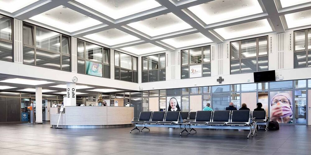 Eingangsbereich des Johanna-Etienne Krankenhauses. In diesem befinden sich Sitzmöglichkeiten und ein Infostand. 