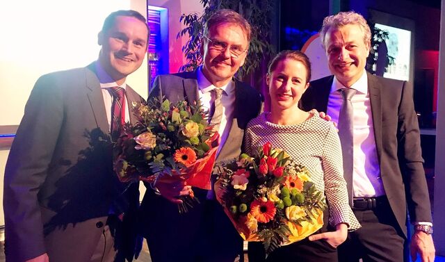 Drei Männer und eine Frau bei einer Preisverleihung. Die Frau und ein Mann haben einen Blumenstrauß in der Hand und alle vier gucken lächelnd in die Kamera.