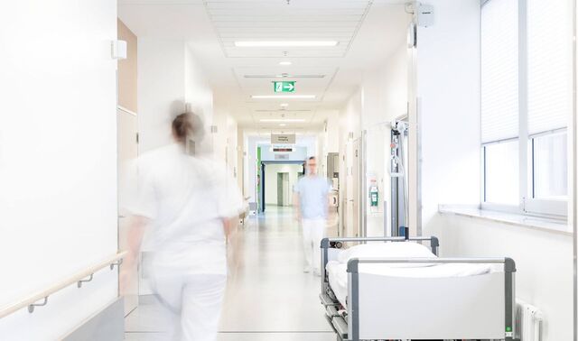 Flur eines Krankenhauses in dem sich zwei Krankenpfleger befinden und ein Patientenbett steht.