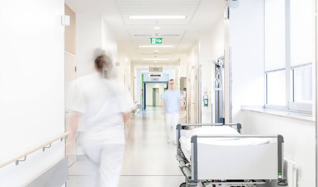 Flur eines Krankenhauses in dem sich zwei Krankenpfleger befinden und ein Patientenbett steht.