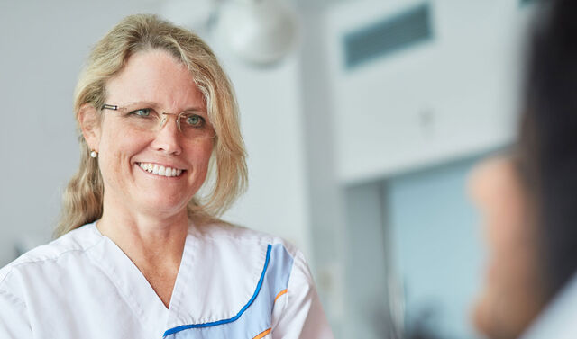 Eine Hebamme lächelt ihre Patientin, welche vor ihr liegt, an.