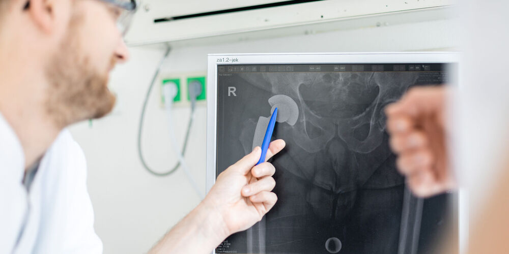 Ein Arzt aus dem Fachbereich Orthopädie erklärt eine Behandlung am Gelenk.