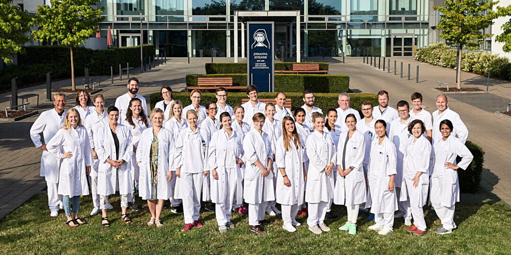 Team der Inneren Medizin des Johanna Etienne Krankenhauses auf einer Rasenfläche vor dem Krankenhaus