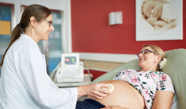 Eine Ärztin führt eine Ultraschalluntersuchung bei einer Schwangeren durch. 
