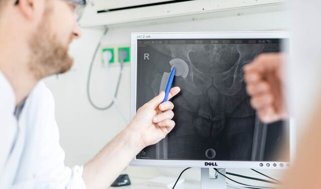 Bild eines Beckens auf einem Computerbildschirm. Ein Arzt zeigt mit einem Stift etwas auf diesem.